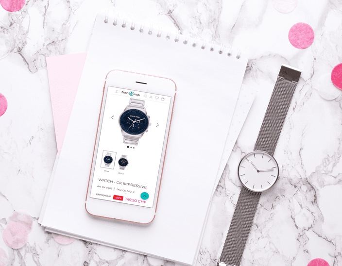 A smartphone resting on a notebook next to a wristwatch, showing the FlashHub product page for a Calvin Klein watch with photos, a variant selector and a price.